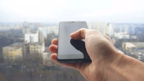 Close-up shot of man texting on smart phone against cityscape Stock Footage 83574802