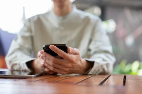 A close-up shot of a man using his smartphone at a table in a cafe. Foto stock