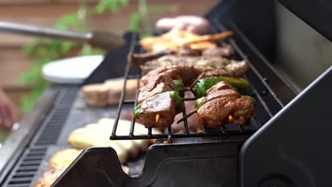 Close up shot of man using tongs to barbeque meat and sausages or bratwurst on a Stock Footage 136735745