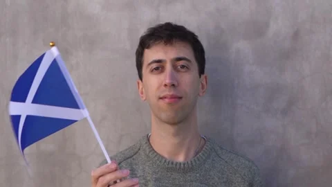 Close up shot of a man waving Scottish flag in slow motion. Scotland country Video stock 336410403