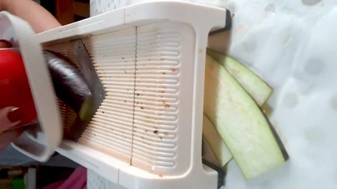 Close-up shot of a mandolade vegetable slicer. Slicing eggplant. Vertical video Stock Footage 253579203