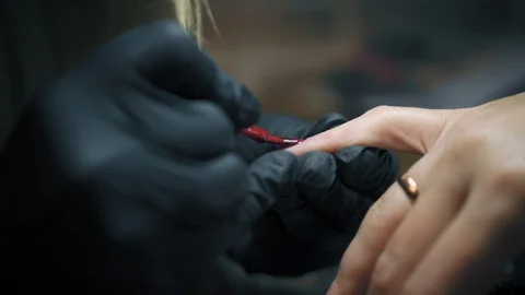 Close up shot of manicure master in black gloves is painting woman's little Stock Footage 93994182