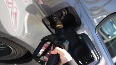 Close-up shot man's hand inserts fuel gun in gas tank to refuel gray car Vidéo 253826042