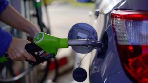 Close-up shot of a man's hand putting fuel nozzle in car's fuel tank. Stock Footage 99555779