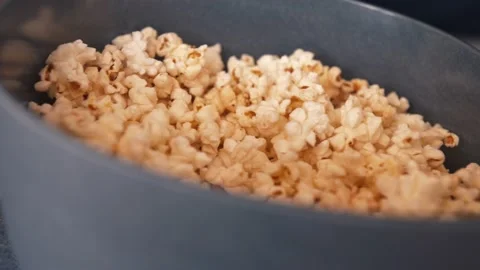 Close-up shot of a man's hand taking popcorn from a bowl while watching TV. Video stock 138904512