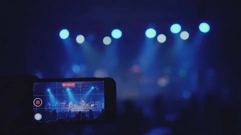 A close-up shot of a man's hand is taking video for a music band on stage. Stock Footage 145125608