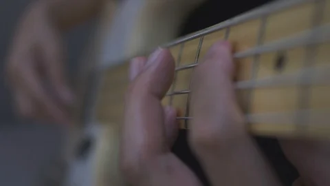 Close-up shot of a man's hands playing an electric guitar bass at home. 動画素材 128242166
