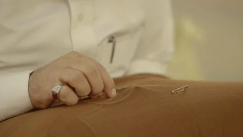Close up shot on man's hands' sewing to Saudi outfit﻿. Stock Footage 113665419