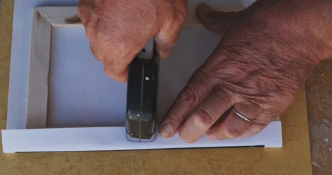 Close up shot of a mans hands stretching and stapling a canvas print on to th Vídeo Stock 208057186