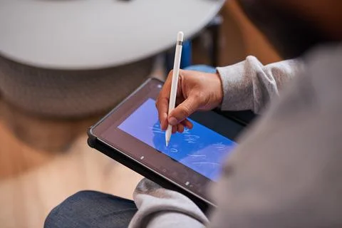A close up shot of a man's hands using a stylus to draw on a tablet Stock Photos