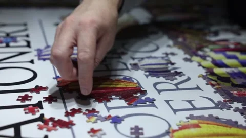 Close-up shot of many jigsaw pieces being put in place building the image Stock Footage 294151825