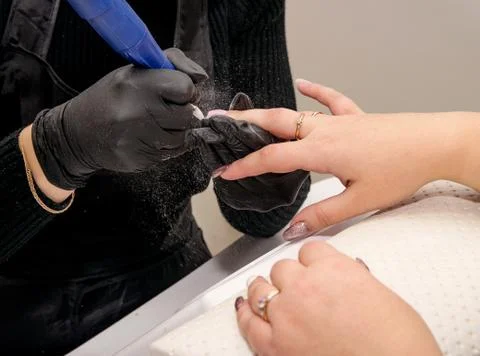 Close-up shot of a master in black gloves removing the coating of gel polish  Stock Photos