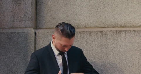 A close-up shot of a middle-aged man in a business suit standing against a stone Video stock 347011628