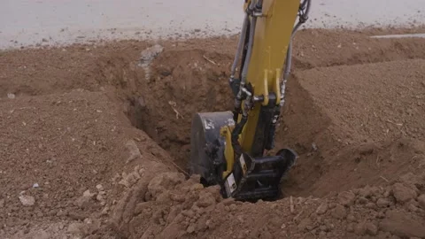 Close up shot of mini excavator digging dirt by sidewalk Stock Footage 227450897