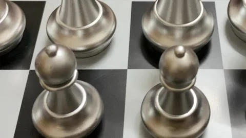 Close up shot: Modern silver chess pawn standing on a black and white board. Stock Footage 333183532