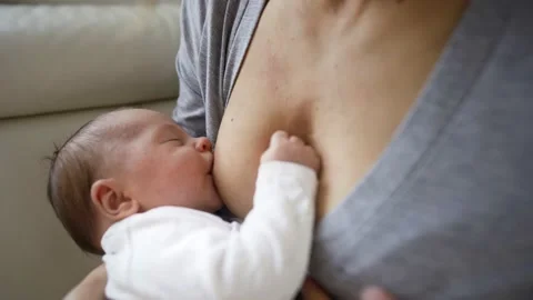 Close Up Shot Of Mother Sitting On Sofa At Home And Breastfeeding Baby Vídeos de archivo 147575377
