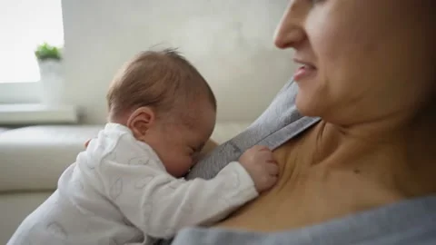 Close Up Shot Of Mother Sitting On Sofa At Home And Breastfeeding Baby Stock Footage 147575596