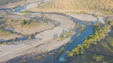 Close-up shot of mountain river with rapids surrounded by  forest and meadow. Video stock 242103663