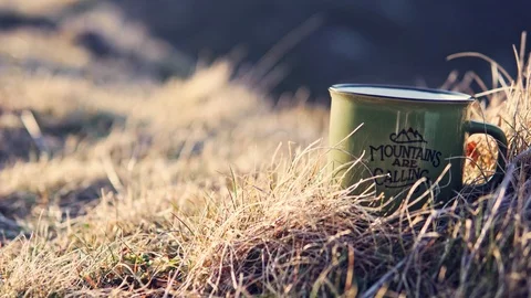 Close-up shot of a mug full of hot tea in golden grass in mountains Stock Footage