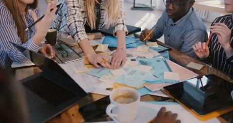 Close-up shot of multiethnic team working together behind table full of notes on Stock Footage 106157665
