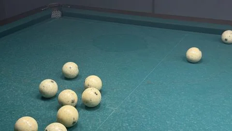 Close up shot of multiple billiard balls gathered near the cushion of a green Stock Photos