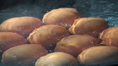 Close-up shot of multiple eggs boiling in a pot of water. Video stock 348207905