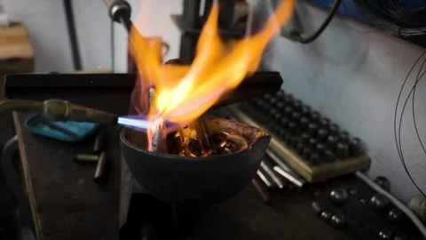 Close up shot of a musical instrument builder melting pieces of lead with Stock Footage 128562202