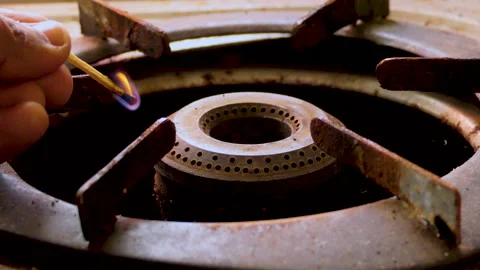 Close shot of an old and dirty gas burner hand turns it on with a matchstick Stock Footage 146803499