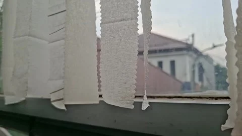 A close-up shot of old, worn-out white vertical blinds hanging in front of .. Vídeos de archivo 332988671