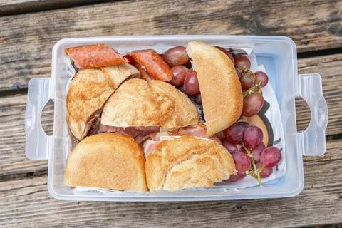 Close-up shot of an open plastic container packed with sliced buns, grilled 库存照片