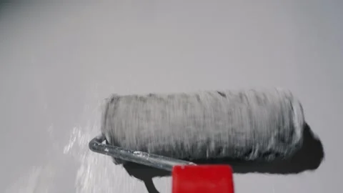 Close-up shot of a paint roller with red handle moving across white wall cr.. Vidéo 335740742