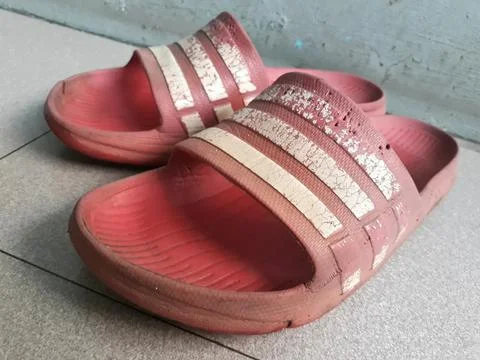 Close up shot of a pair of old red worn plastic sandals Stock Photos