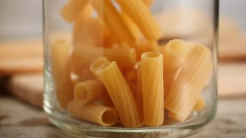 Close up shot of pasta falling into a jar in slow motion Stock Footage 156810199