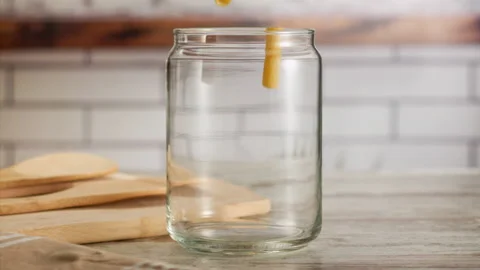 Close up shot of pasta falling into a jar in slow motion Stock Footage 156810411