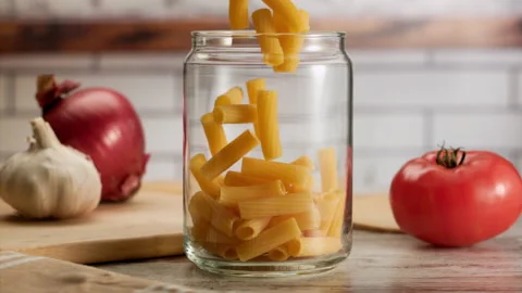 Close up shot of pasta falling into a jar in slow motion Stock Footage 156872725