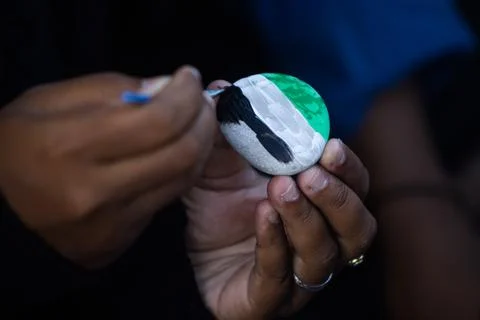 Close Up Shot of Person Adding Black Strokes to Green and White Painted Peb.. 写真素材