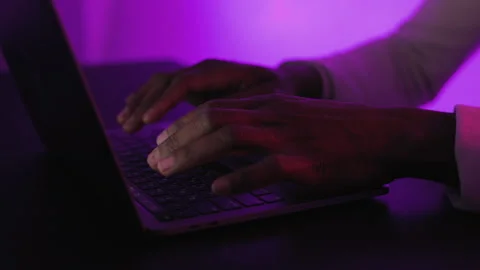 Close-up shot of a person hands typing on a laptop keyboard, illuminated by Stock Footage 289072107