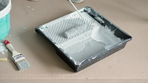 A close-up shot of a person loading a paint roller from a tray Stock Footage 232365524