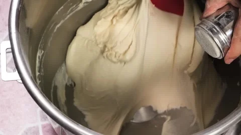 Close-up shot of a person mixing bread dough in a large metal bowl with a red sp Stock Footage 331632556