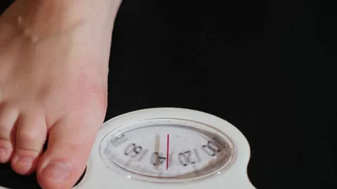 A close up shot of a person stepping onto an old analog scale, measuring th.. Stock Footage 334828821