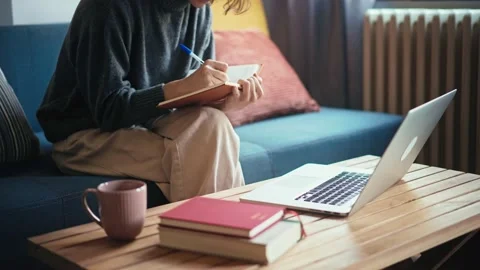 Close-up shot of a person taking notes in the notebook and typing on a laptop Stock Footage 222062672