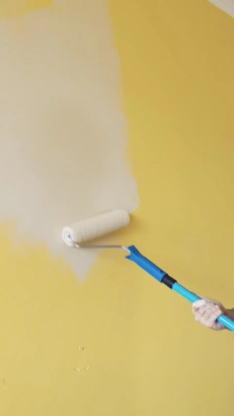 Close-up shot of a person using a paint roller to apply white paint onto a .. Stock Footage 337597609