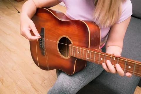 A close-up shot of a person's hands installing new bronze strings on a brown  Stock-Fotos