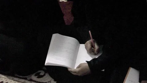 A close-up shot of a person's hands writing with a pen in an open notebook Stock Footage 343731632