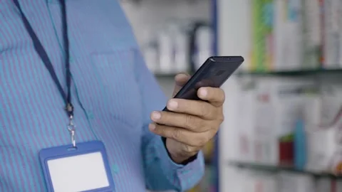 Close up shot of Pharmacist busy using mobile phone at retail pharma medical sto Vidéo 172584692
