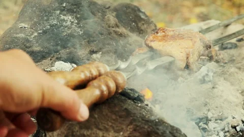 A close-up shot of a piece of meat being grilled over a campfire. The meat .. Stock Footage 300878293