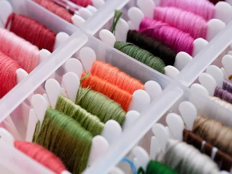 A close-up shot of a plastic sorting box full of bobbins with different colou Stock Photos