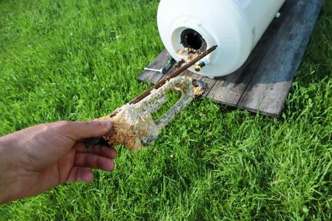 A close-up shot of a plumber's hand showing a corroded boiler heating element Stock Photos