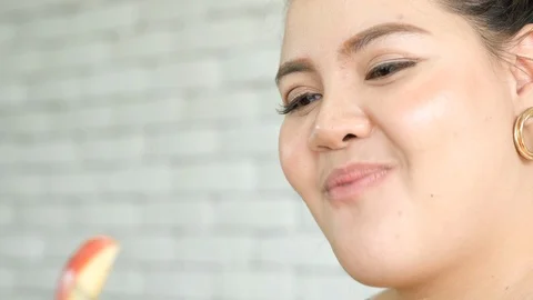 Close up shot of plus size or big size girl is eating the pieces of apple Stock Footage 120718941