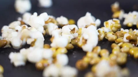Close-up shot of popcorn popping, exploding in slow motion in a pan Stock Footage 277564047